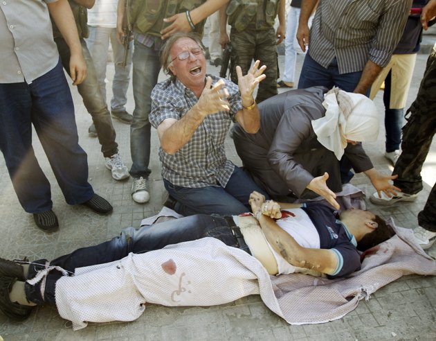 A mother and father look over the body of their son killed in the Salah Eddine neighbourhood of Aleppo