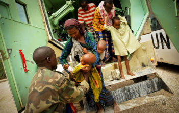 A Somali woman hands her severely malnourished child to an African Union medical officer