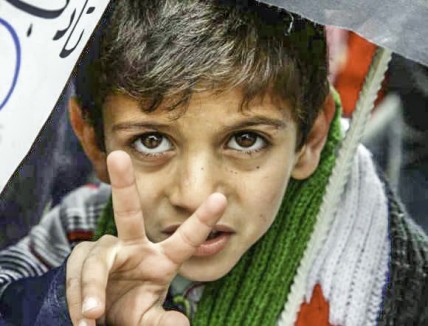A young boy joins hundreds of refugees as they protest in Yayladagi, Turkey, against Assad's regime