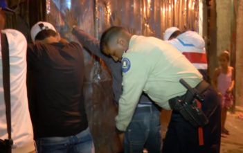 Venezuelan police officer searches suspected gang members