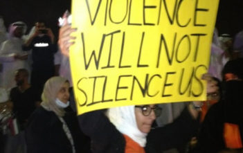 A Kuwaiti blogger holding a banner saying "Violence will not silence us"