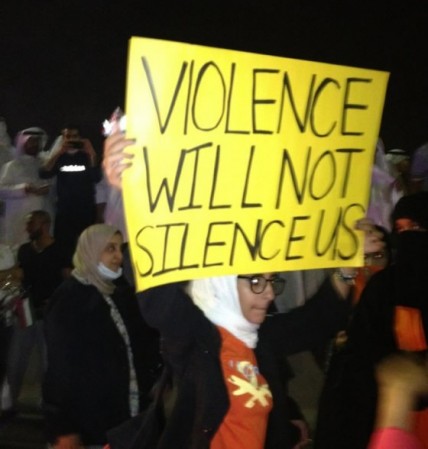 A Kuwaiti blogger holding a banner saying "Violence will not silence us"