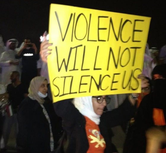 A Kuwaiti blogger holding a banner saying "Violence will not silence us"