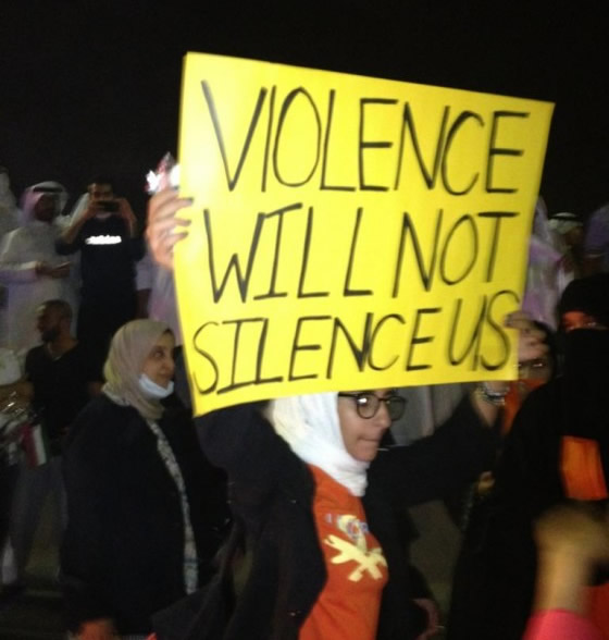 A Kuwaiti blogger holding a banner saying "Violence will not silence us"