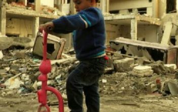 A child plays on a destroyed street in Homs, Syria
