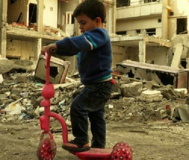 A child plays on a destroyed street in Homs, Syria