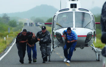 Police take a suspected drug trafficker off a helicopter in Mexico