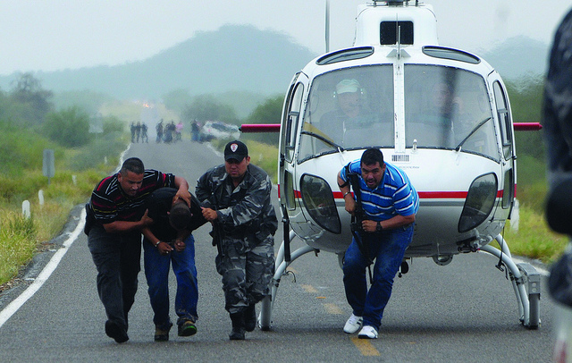 Police take a suspected drug trafficker off a helicopter in Mexico