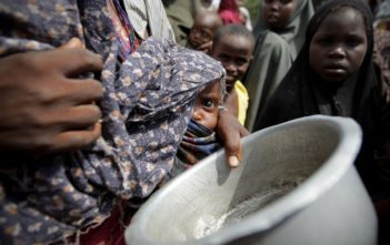 A woman holding her young malnourished baby queues for food in Somalia
