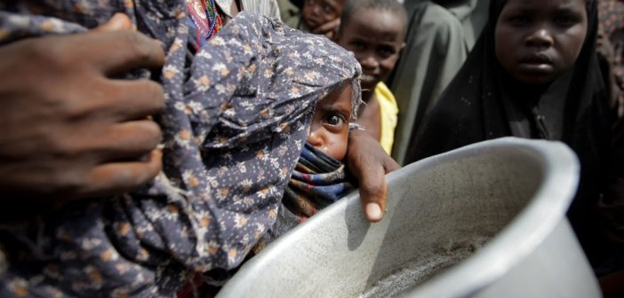 A woman holding her young malnourished baby queues for food in Somalia