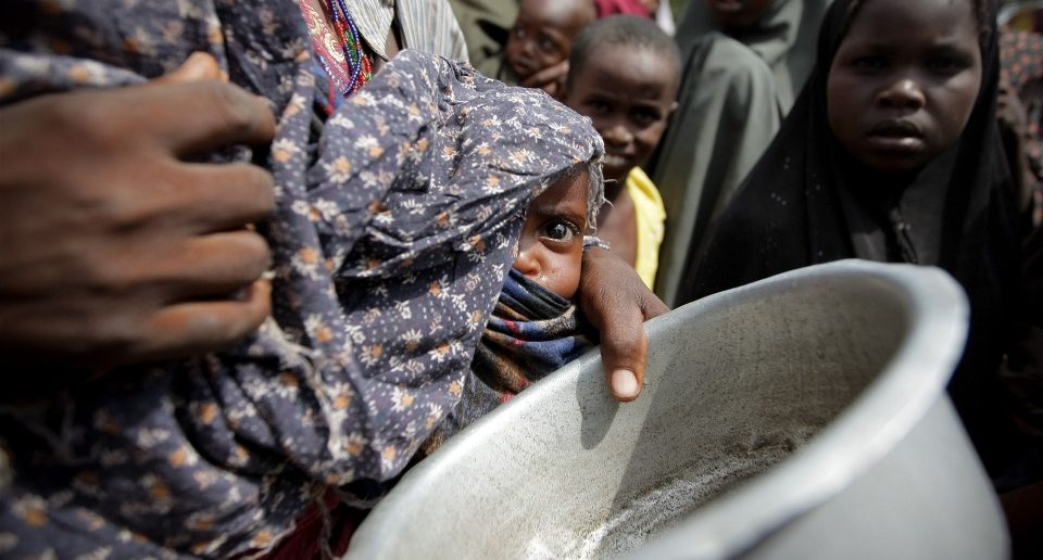 A woman holding her young malnourished baby queues for food in Somalia