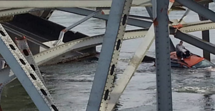 A man sits on the roof of his car awaiting rescure after the bridge collapse