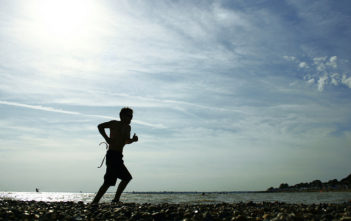 Man runs along a pebble beach