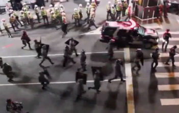 Riot police rushing towards peaceful protesters chanting "no violence"