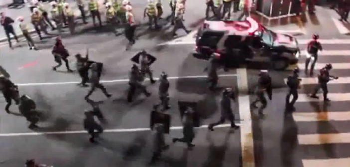 Riot police rushing towards peaceful protesters chanting "no violence"