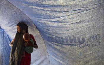 A Somali refugee stands inside a tent with her baby in Dollo Ado, Ethiopia
