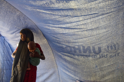 A Somali refugee stands inside a tent with her baby in Dollo Ado, Ethiopia
