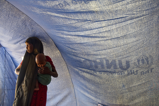 A Somali refugee stands inside a tent with her baby in Dollo Ado, Ethiopia