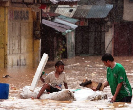 Father and son wade through flood water in Manila in 2012