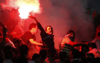 Football fans throw flares to celebrate a goal