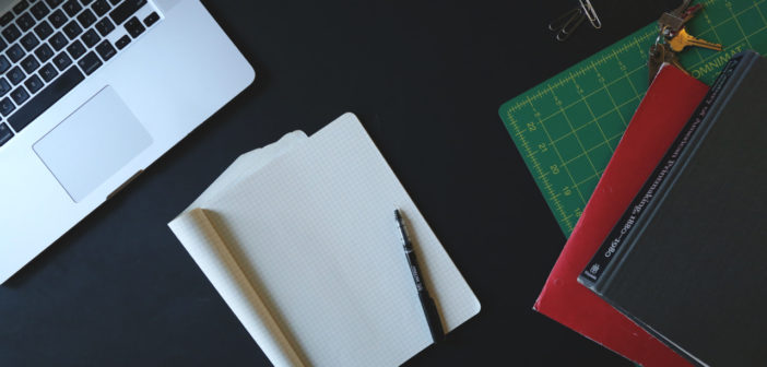 Laptop, pens, and paper in business office